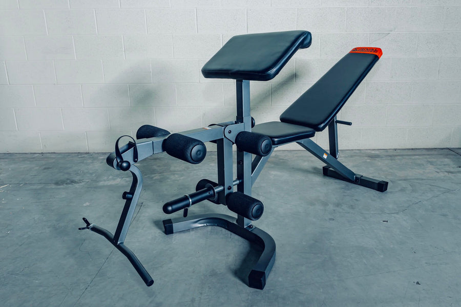 Adjustable bench with preacher curl bar and leg extension for versatile workouts at home gym.